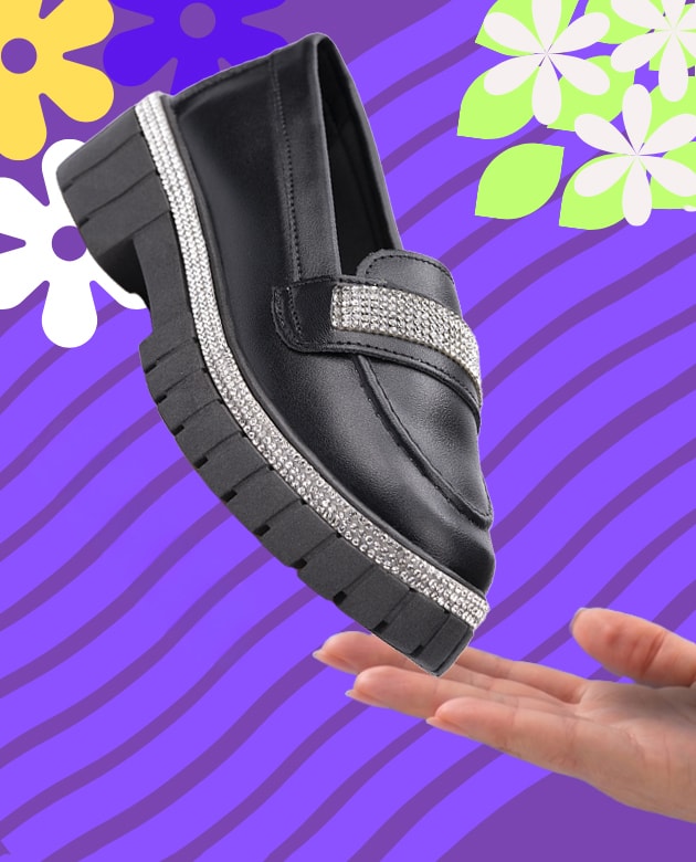 Mocassim infantil feminino preto com sola tratorada grossa. O modelo apresenta detalhes em tiras de strass brilhantes ao longo da costura da sola e na faixa sobre o peito do pé.
