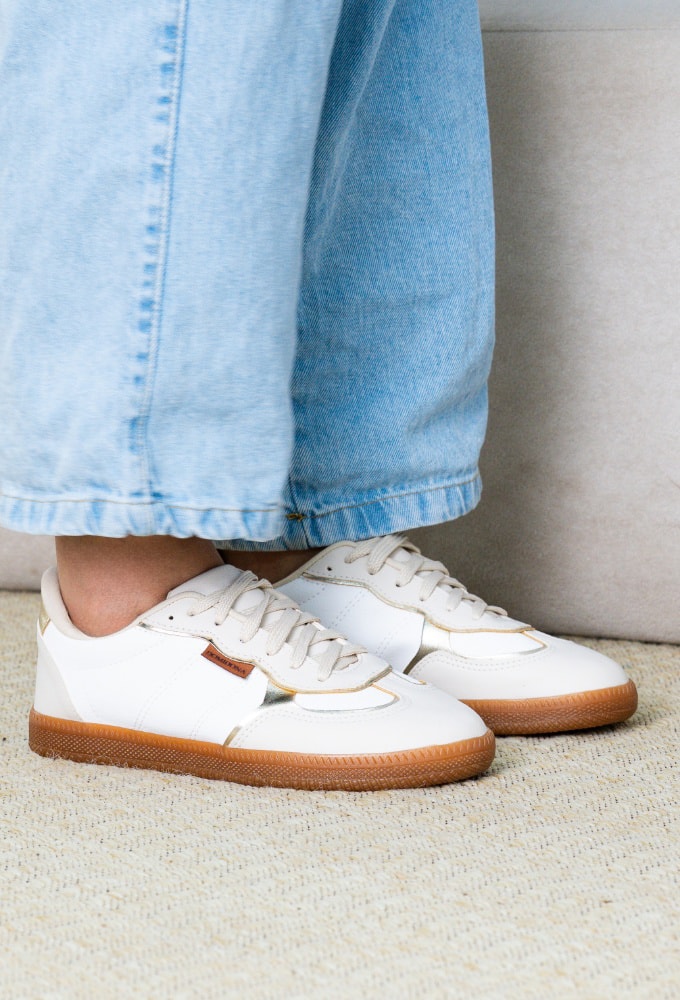 Mulher com look moderno usando o Tênis Feminino Retrô Branco com Detalhe Dourado Domidona